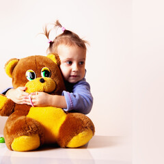 Smiling child holding a soft teddy bear while posing for a playful portrait.
