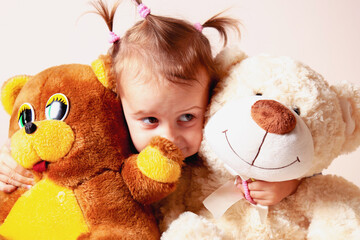 Child hugging two large teddy bears with a warm smile.