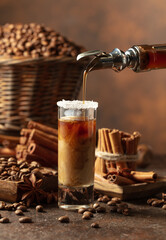 Coffee liqueur is poured from a bottle into a glass with cream.