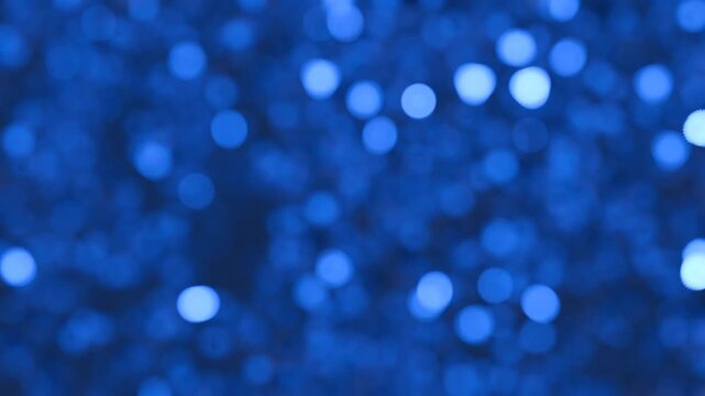 Glitter rain. Blue background with sparkling tinsel and bokeh effect, seamless loop. Festive background for winter holidays, Christmas, any  celebrations. 3D animation, motion graphic, 4k resolution
