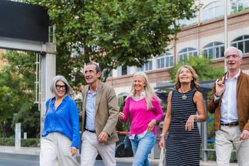 Obraz premium Mature friends walking together enjoying urban street lifestyle