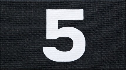 Bold white number five on black canvas fabric background
