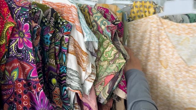 A woman selects batik fabric while shopping in a Yogyakarta store in the afternoon
