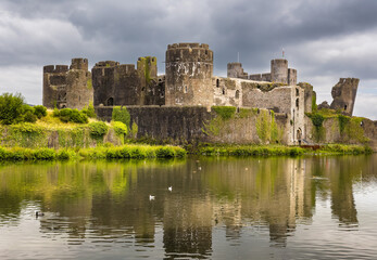 Ivy-covered stone walls of a 13th-century Norman castle under a dramatic cloudy sky