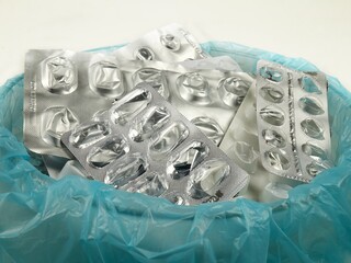 Heap of empty pill blister packs in a special container for disposal,  used pill pack blisters, side view. Treatment and medication concept