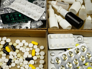Expired medications, blisters, and used medication vials in boxes, preparing for disposal. Treatment and medicines concept
