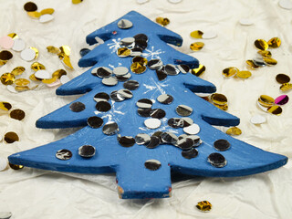 Gold confetti are on a Blue Christmas tree, lying on a white background from craft paper, handmade. Christmas composition, greeting card