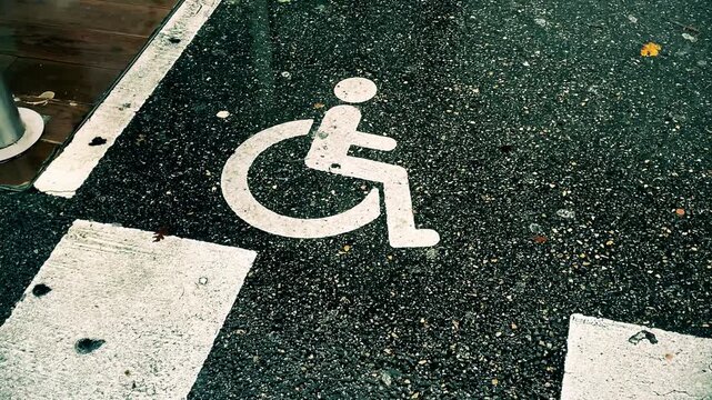 Wheelchair symbol on asphalt road marking. Concepts of accessibility, mobility, public infrastructure, and transportation