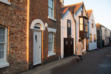 Woman walking along historic street at sunset. Whitstable kent England