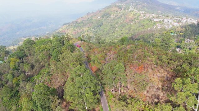 Scenic Drone View of Red Bus on Calm Mountain Road in Fresh Morning Landscape