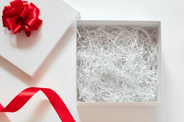 open box with filler, white square gift box with a red bow and an open lid, Valentine's Day gift