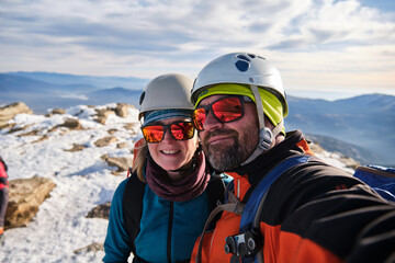Couple of mountaineers taking a selfie at the summit after climbing.