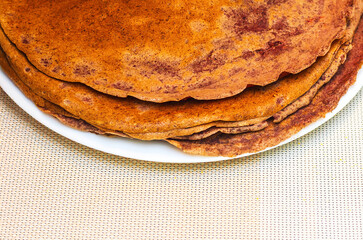 Stack of delicious pancakes on a white plate, ready to be eaten