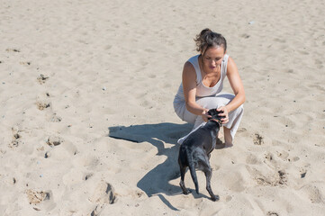 Caucasian woman walking on the beach with her dog.