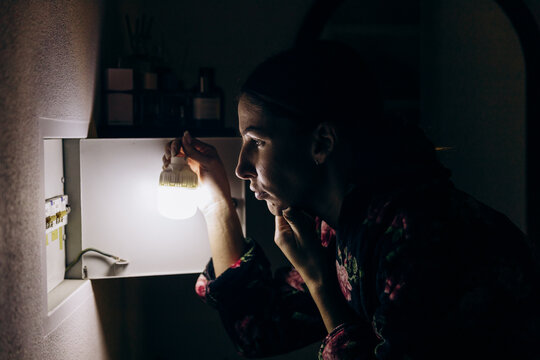 The lights and electricity go out in the apartment. A girl stands near the fuse box and thinks.