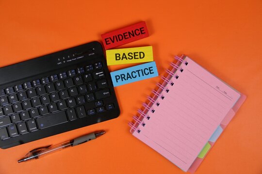 orange background with a keyboard, pink spiral notebook, and colorful wooden blocks showing 'Evidence Based Practice'.perfect for education, study, and professional learning contexts.