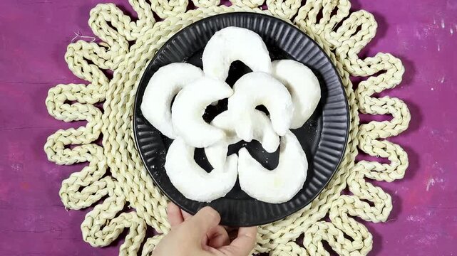 Oriental Algerian sweet cookies named tcharek aryen in arabic which mean almond cookies in english  On Black Plate With Hands, Rustic Woven Mat 