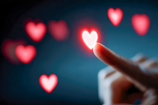 Human finger touching glowing heart-shaped light with multiple red hearts floating in a soft dark background symbolizing love and connection concept - Powered by Adobe