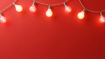 A festive border of glowing string lights draped across the top of a vibrant red background, creating a holiday frame with ample copy space for Christmas or Valentine's Day messages.