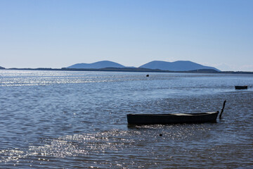 Small wooden boat moored in Narta Lagoon, Albania. Beautiful coastal landscape with a lake and distant mountains