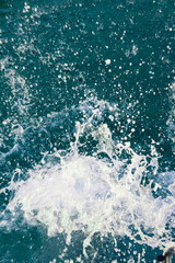 Turquoise sea water with foam splashes after jump from a boat. Fresh summer ocean background, travel, recreation and vacation concept