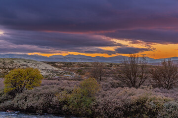Fiery sunset sky over autumn tundra river in Rondane National Park Norway