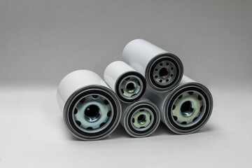 Several white spin-on oil filters arranged horizontally on neutral background, ideal for automotive maintenance catalog or engine-parts ecommerce presentation as clean product display.