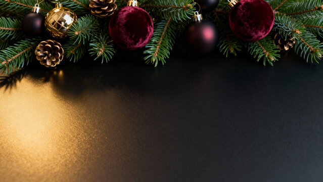 Christmas decorations with green fir branches, red and gold ornaments, black background, copy space