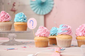 Delicious cupcakes with question mark and decorations on table against pink background. Gender reveal party concept
