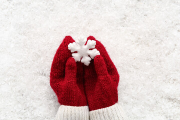 Female hands in red warm mittens with decorative snowflake on snow