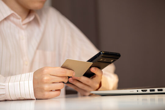 Close-up of a person holding a credit card while using a laptop, representing online shopping, digital payments, and secure internet transactions in a modern workspace
