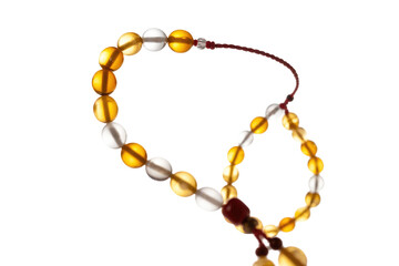 Elegant amber and clear beaded prayer beads (tasbih) with a red string and tassel, set against a transparent background. background removed