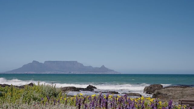 Waves break onto Blouberg shore, with stunning views of Table Mountain, Devil&rsquo;s Peak, and Signal Hill in Cape Town, Western Cape, South Africa. Perfect coastal nature footage in 4K 30fps.