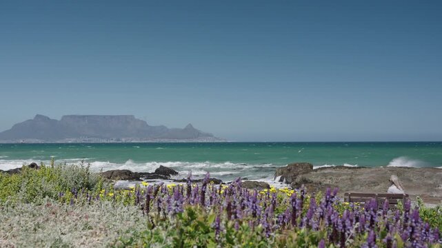 Waves break onto Blouberg shore, with stunning views of Table Mountain, Devil&rsquo;s Peak, and Signal Hill in Cape Town, Western Cape, South Africa. Perfect coastal nature footage in 4K 30fps.