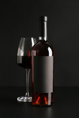 Bottle and glass of red wine on black background
