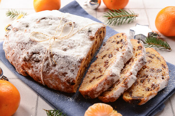 Tasty Christmas stollen on white tile background
