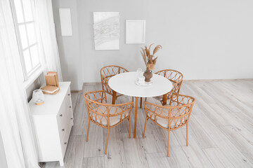 Interior of stylish dining room with paintings, drawers and table
