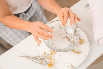 Mature woman preparing steam inhalation with herbs in bedroom, closeup