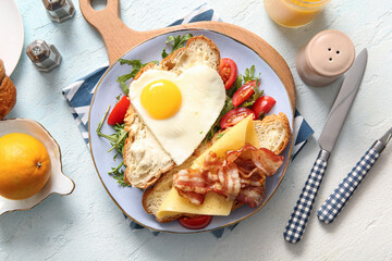 Plate with tasty fried egg, cut croissant, bacon, tomatoes and arugula on light background