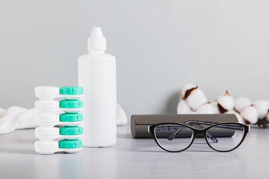 Concept of choosing between glasses and contact lenses on a table