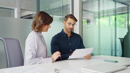 Businesswoman and businessman reading paperwork document in office. Latin woman accountant analyst holding document working with European client man doing trade market financial data base bank report - Powered by Adobe