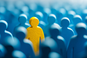 A single yellow figure standing out prominently among numerous blue figures symbolizing individuality and uniqueness in a crowd setting with soft focus background