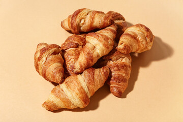 Many tasty croissants on brown background