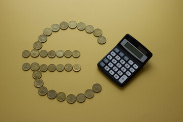 Euro symbol made of coins with calculator on yellow background