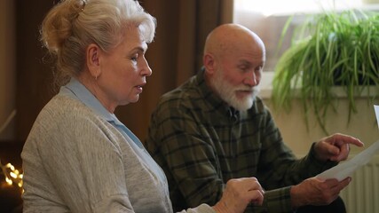 Senior couple planning family budget, reading utility bill and counting money