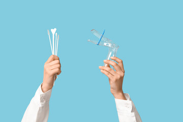 Doctor's hands with pap test tools on blue background