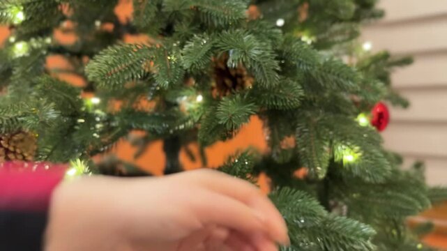 A couple decorates a Christmas tree with ornaments and lights in a cozy apartment. The video captures the festive mood and joyful holiday preparation.