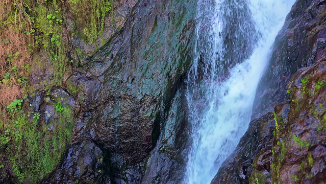Mossy rocks and a waterfall, rushing torrent.