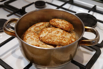 Meat cutlets are stewed in saucepan after being fried in a frying pan. Cooking