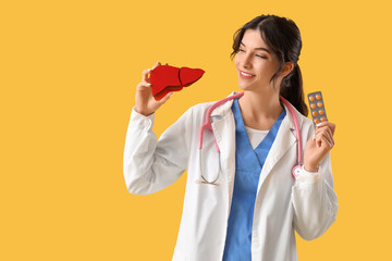 Female doctor with paper liver and pills on yellow background